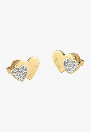 Goldfarbene herzförmige Ohrstecker, wobei eine Seite mit klaren Strasssteinen verziert ist und die andere mit "GUESS" graviert ist. Glatte Oberfläche, polierter Finish.