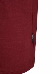 Bordo T-särk, mis on valmistatud pehmest puuvillast, küljeõmbluse sildiga ja siledast tekstuurist, lihtsalt ja puhtalt disainitud.