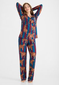 Ensemble de pyjama bleu et bordeaux avec un imprimé tigre sur toute la surface. Le tissu est doux avec un haut à boutons et un pantalon ample.