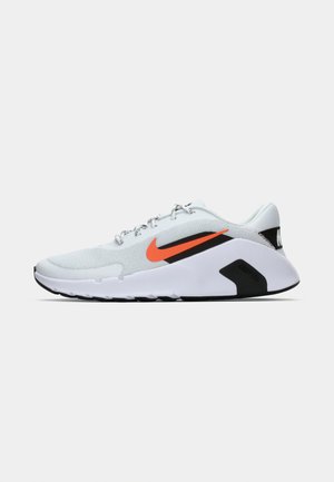 Hvid sportssko med struktureret mesh-overdel, der har et orange Nike-logo, sorte accenter og en polstret sål med sorte og hvide detaljer.