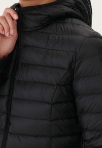 Czarna puchowa kurtka z zamkiem błyskawicznym, poziomym pikowaniem i kapturem. Materiał jest błyszczący i lekki.