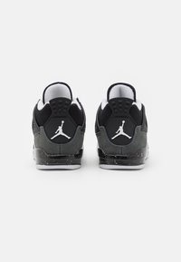 Juodos ir pilkos sportbačiai su zomšiniu ir tinkliniu viršumi, baltais logotipais ir margintu juodu tarpiniu pado. Kulno dalyje matomas Jumpman logotipo detalė.