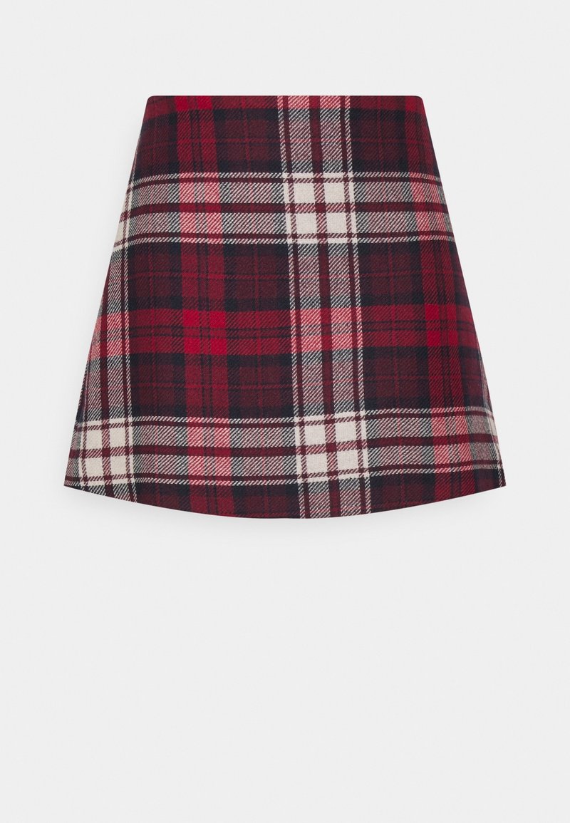 Jupe mini patineuse en tartan rouge et noir avec des rayures blanches et roses entrecroisées sur un fond uni clair.