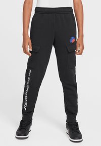 Sudadera negra de algodón con cintura elástica, bolsillos tipo cargo y un logo de Nike en rojo y azul. Presenta texto blanco a lo largo de la pierna izquierda.