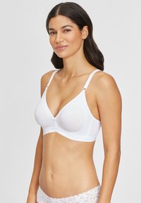 White cotton triangle bra featuring soft cups, adjustable straps with circular hardware, and a lace band detail at the base.