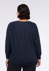 Maglione blu navy con trama scintillante, scollo ampio e maniche lunghe. Il design presenta una vestibilità comoda e spacchi laterali all'orlo.