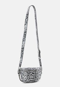 Torebka crossbody w wzór węża w czerni i bieli, o zaokrąglonym kształcie, z regulowanym paskiem i kieszonką na zamek z przodu. Gładka tekstura.