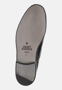 Semelle de chaussure en cuir noir avec finition lisse, comportant le texte embossé "HENRY STEVENS BERLIN," taille "10," et des clous en laiton près du talon.