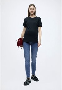 Μαύρο κοντομάνικο μπλουζάκι συνδυασμένο με μπλε τζιν, μαύρα πλατφόρμα παπούτσια και κόκκινη τσάντα χειρός, πάνω σε ανοιχτό φόντο.