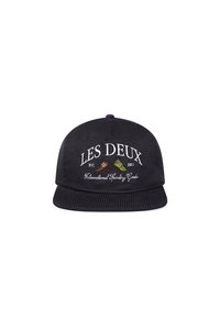 Black corduroy cap with a flat brim, embroidered text "LES DEUX" and graphics in contrasting colors, featuring textured fabric.