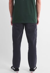 Pantalon cargo gris foncé en coton, doté de poches latérales, de poignets élastiques et d'une coupe ample. À associer avec des baskets noires.