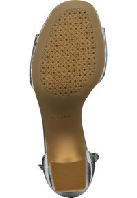 Zilveren pump met een gestructureerd bovenwerk, uitgerust met een rubberen zool met een patroon voor grip en subtiele GEOX-merken op de hak.