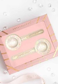 Due strumenti per massaggi facciali in cristallo iridescente, riposti in una scatola rosa, con forme rotonda e ovale, caratterizzati da accenti dorati e una texture liscia.