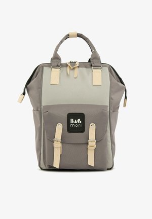 Pelēka auduma mugursoma ar diviem augšējiem rokturiem, krēmkrāsas akcentiem, priekšējo kabatu ar vāku un logo uzlīmi; tai ir strukturēts dizains.