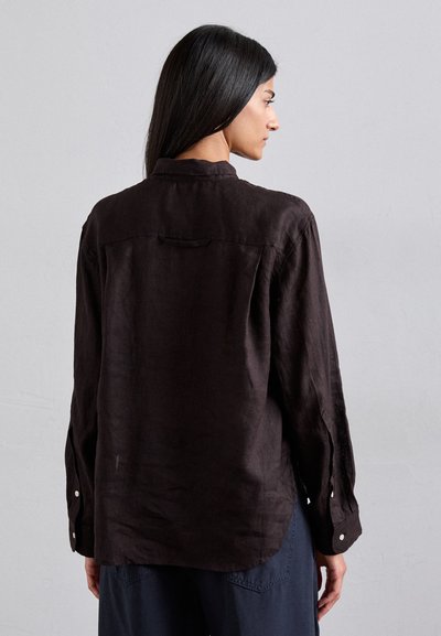 Chemise en lin brun foncé avec col, manches longues et un empiècement dans le dos. Présente des accents de boutons argentés aux poignets.