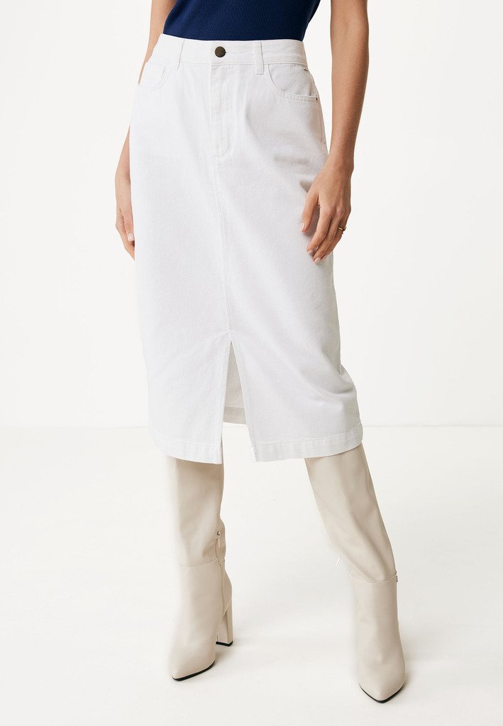 Falda midi de mezclilla blanca con abertura frontal y cierre de botón tradicional, combinada con botas beige hasta la rodilla. Textura suave, corte recto.