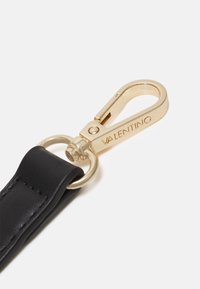 Svart läderband med klämma i guldmetall. Klämman har en rundad ände och en gravyr av märkesnamnet "VALENTINO." Slät textur.