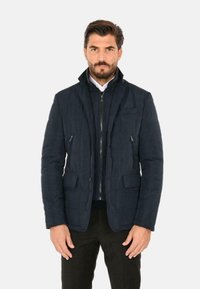 Giubbotto imbottito blu navy realizzato in tessuto testurizzato, con chiusura a zip, due tasche frontali e colletto alto per maggiore calore.