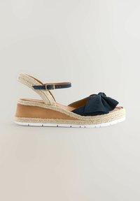 Sandalo wedge in suede blu con dettaglio a fiocco, rifinitura in juta, cinturino alla caviglia regolabile e suola in gomma bianca. Design classico espadrille.