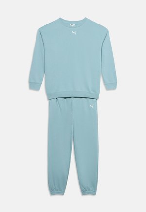 Lichtblauw Puma-trainingspak met een sweater met lange mouwen en bijpassende joggingbroek, beide met witte Puma-logo's op de borst en dij.