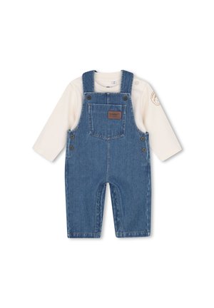 Conjunto de bebé con camiseta de manga larga color crema y peto vaquero azul con botones en los laterales y un bolsillo delantero con una etiqueta marrón.