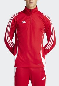 Red athletic zip-up jacket with white accents and three stripes design on sleeves, made of smooth fabric, featuring a high collar.