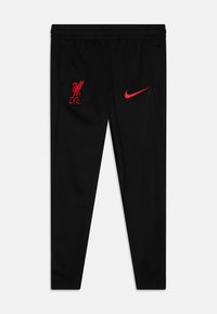 Pantalon de sport noir en tissu léger, avec le logo rouge de Liverpool FC et le swoosh rouge de Nike sur la cuisse gauche. Ceinture élastique.