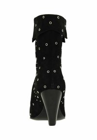 Bottine en daim noir à bout pointu, ornée d'œillets argentés et d'un revers plié. Le talon est une semelle compensée noire effilée.