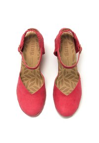 Scarpe rosse in suede con una cinghia intrecciata alla caviglia, punta a forma di V e solette imbottite con motivo a foglia. Presentano un dettaglio con fibbia dorata.