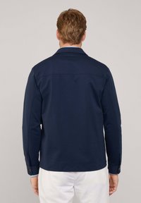 Granatowa koszula z bawełny z dodatkiem innych włókien, z kołnierzykiem, długimi rękawami i zapięciem na guziki przy mankietach. Gładka tekstura, minimalistyczny design i dopasowany krój.