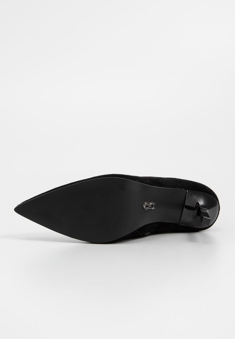 Schwarzer spitzer High Heel-Schuh von der Sohle betrachtet, mit schlankem Stiletto-Absatz und glattem, strukturiertem Boden.
