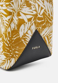 Tropiskt bladtryck tygväska med hörn av svart läder och guld Furla-logotyp präglad på läderflickan.