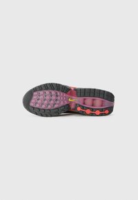 Nike potplat tenisice s crnom gumom, ružičastim međupotplatima i okruglim crvenim detaljima, s malim žutim logotipom sa strane.