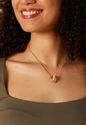 Gouden ketting met een ronde hanger voorzien van een heldere kristallen band. De hanger heeft een gepolijste afwerking en is opgehangen aan een delicaate ketting.