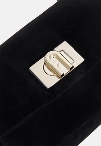 Schwarze Wildleder-Handtasche mit einem polierten goldenen rechteckigen Schlossverschluss. Die Oberfläche ist weich mit einer glatten Textur und minimalen Nähdetails.