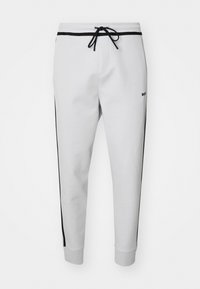 White sweatpants with black side stripes, elastic waistband, and adjustable drawstring. Features cuffed ankles and subtle logo detail.