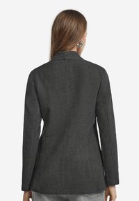 Antracytowa marynarka wykonana z teksturowanej tkaniny, charakteryzująca się dopasowanym krojem, długimi rękawami i klapami. Czyste linie i minimalne detale.