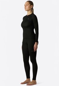 Svart termisk underställsset med långärmad topp och åtsittande leggings, tillverkad av mjukt, stretchigt material med logotypdetaljer.