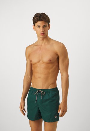 Türkise Badehosen mit einem elastischen Bund, Kordelzug in Pink und Beige sowie einem kleinen Logo auf der unteren linken Seite. Glatte Stofftextur.