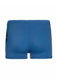 Bañadores azules con una textura suave, que presentan un logotipo negro en el lado izquierdo. El diseño es simple, con una forma ajustada y sin componentes visibles de sujeción.