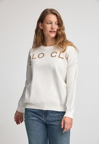Weißer Pullover mit rundem Ausschnitt und langen Ärmeln; mit dem Schriftzug "POLO CLUB" in einer kontrastierenden beigen Farbe über der Brust.