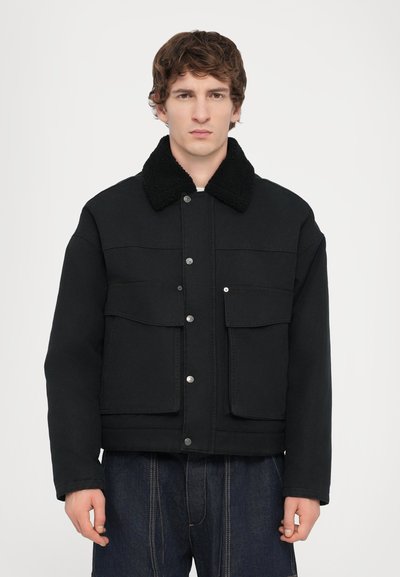 Veste en denim noir avec un col en shearling texturé noir, boutons-pression à l'avant et deux poches poitrine. Présente un design boxy et des manches larges.