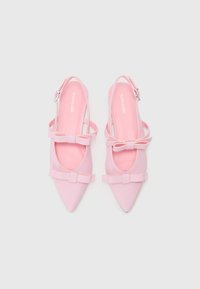 Chaussures slingback roses à bout pointu avec une texture lisse, présentant deux nœuds sur les côtés et une bride de cheville avec une boucle en argent.