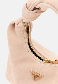 Sac à main en daim rose pâle avec une poignée torsadée, des ferrures en or et une fermeture éclair. Comprend une plaque de logo triangulaire sur le côté.