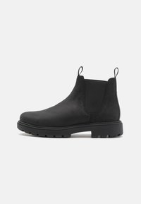 Bottines Chelsea en cuir noir avec des côtés élastiques, des onglets de tirage, une pointe ronde et une semelle en caoutchouc robuste. Texture lisse et design minimaliste.