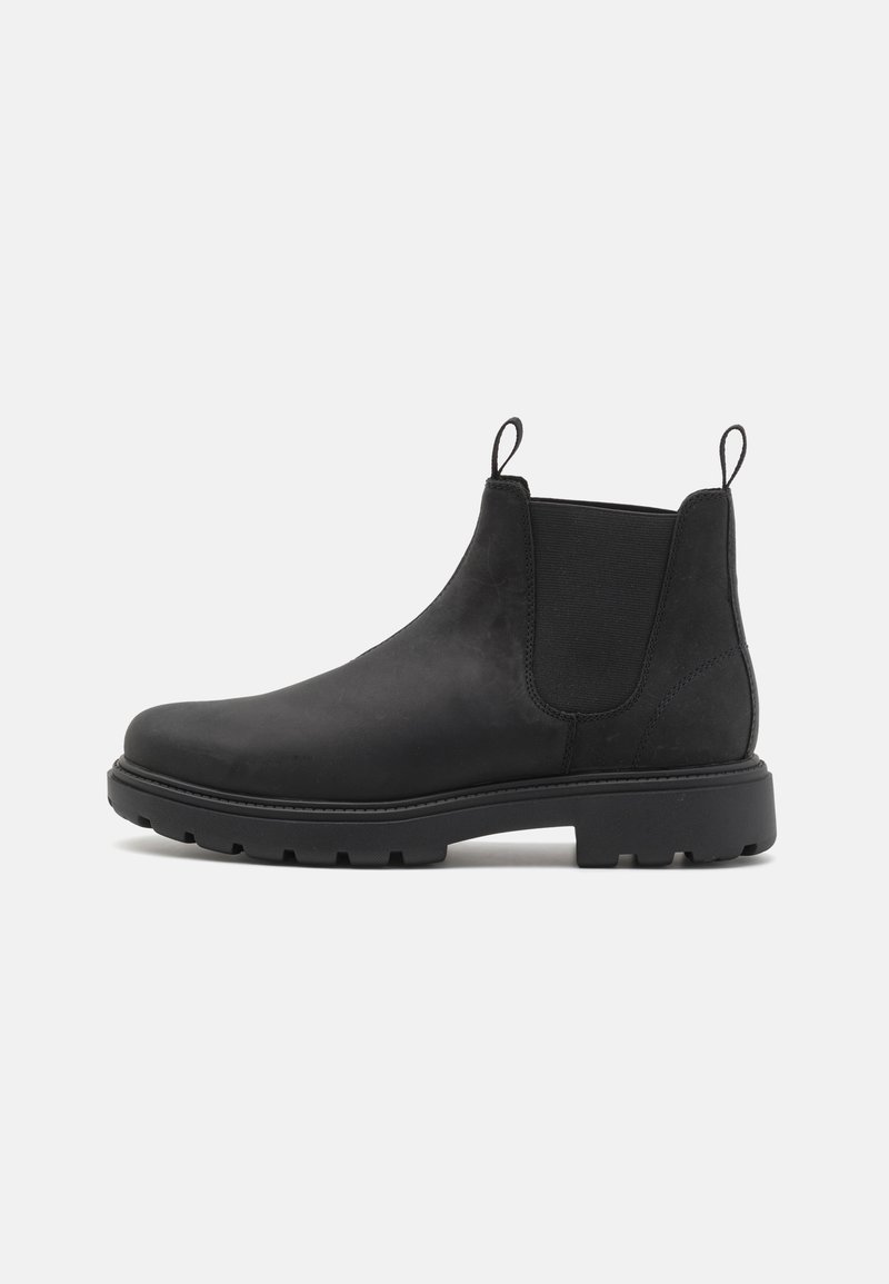 Bottines Chelsea en cuir noir avec des côtés élastiques, des onglets de tirage, une pointe ronde et une semelle en caoutchouc robuste. Texture lisse et design minimaliste.