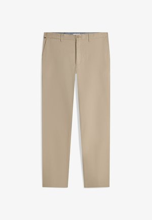 Pantalon beige slim avec passants pour ceinture, fermeture par boutons, poches latérales et petit détail de drapeau près de la poche droite.