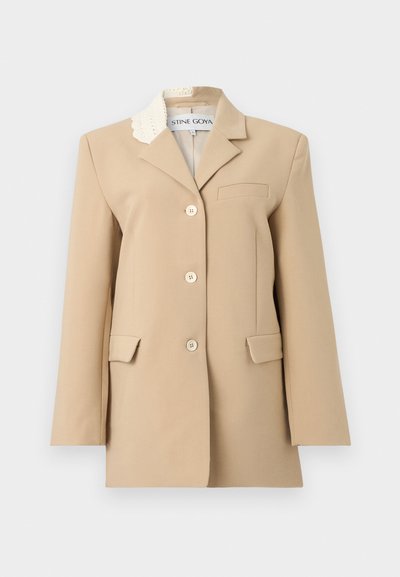 Μπεζ σακάκι με εφαρμοστή γραμμή, τρία κουμπιά, γιακά με εγκοπή, δύο εμπρόσθιες τσέπες με καπάκι και διακοσμητική εκρού δαντελένια λεπτομέρεια στο γιακά.