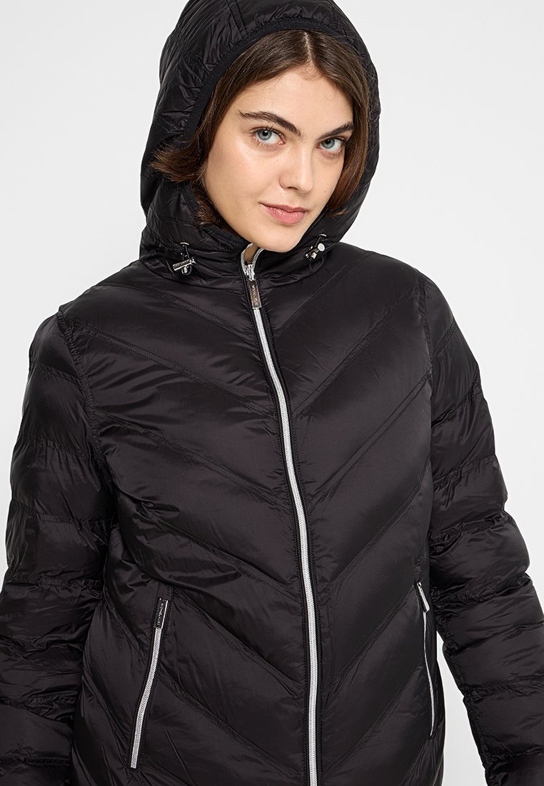 Doudoune noire avec capuche, présentant un design en chevrons quiltés, une fermeture éclair à l'avant et deux poches latérales. Texture lisse et finition brillante.