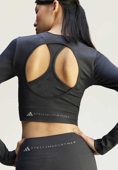 Zwarte cropped top met lange mouwen en een ronde uitsnijding op de rug, gemaakt van textuurstof en met een reliëf logo van het merk aan de zoom.